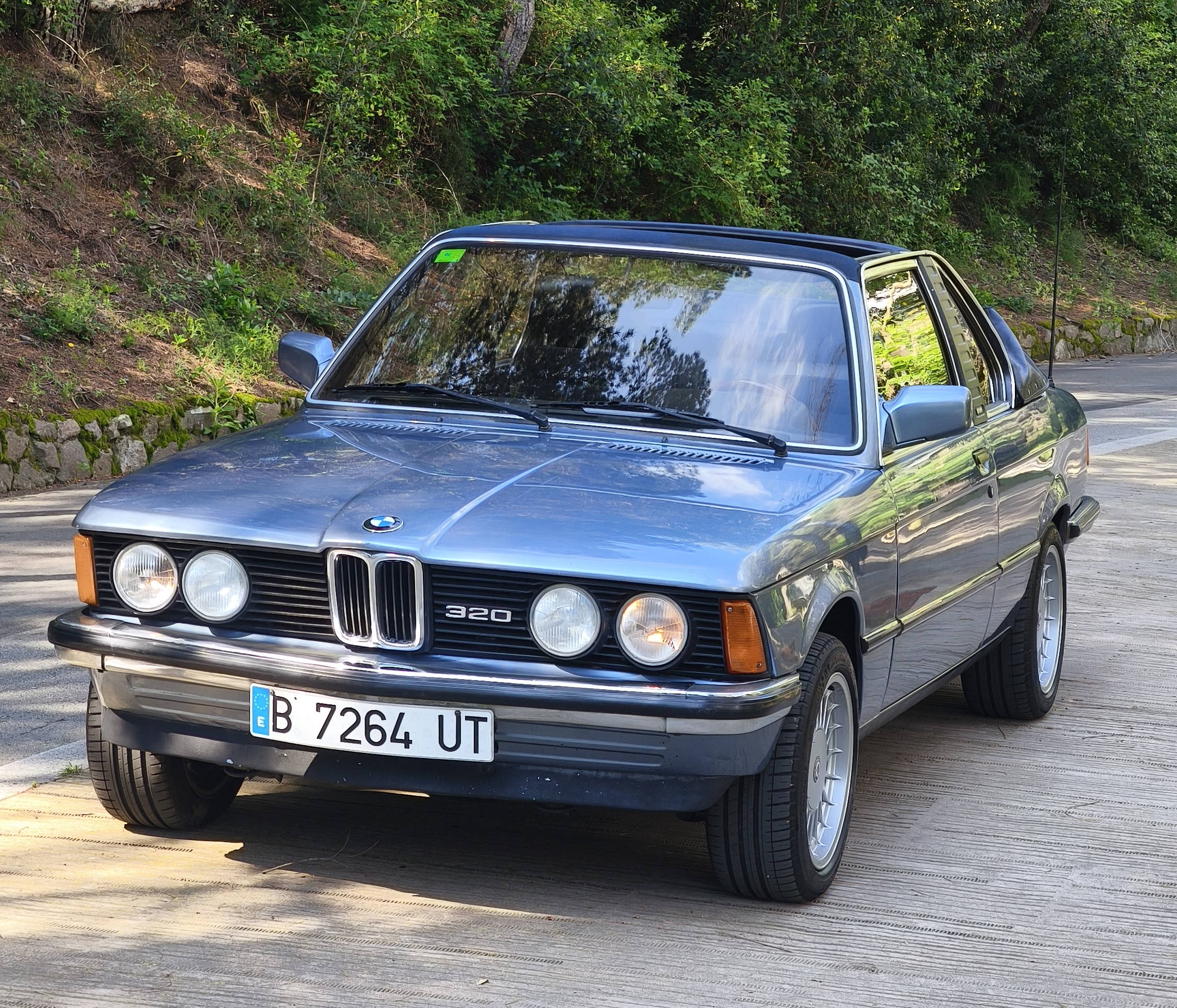 BMW E21 en una carretera rodeada de bosque — localización para rodaje de época