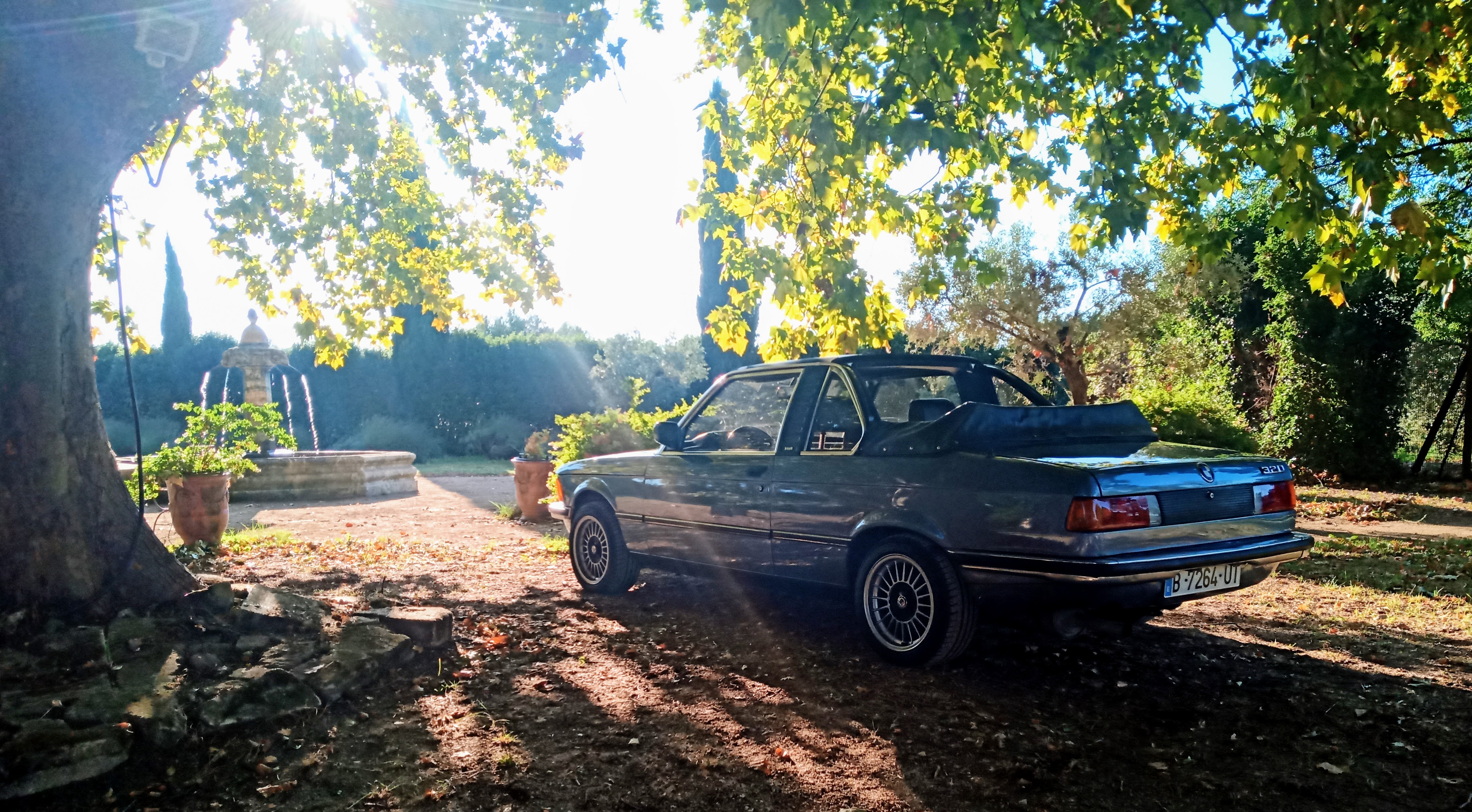 BMW E21 con la capota Baur bajada en un jardín soleado — contexto para bodas y sesiones de retrato